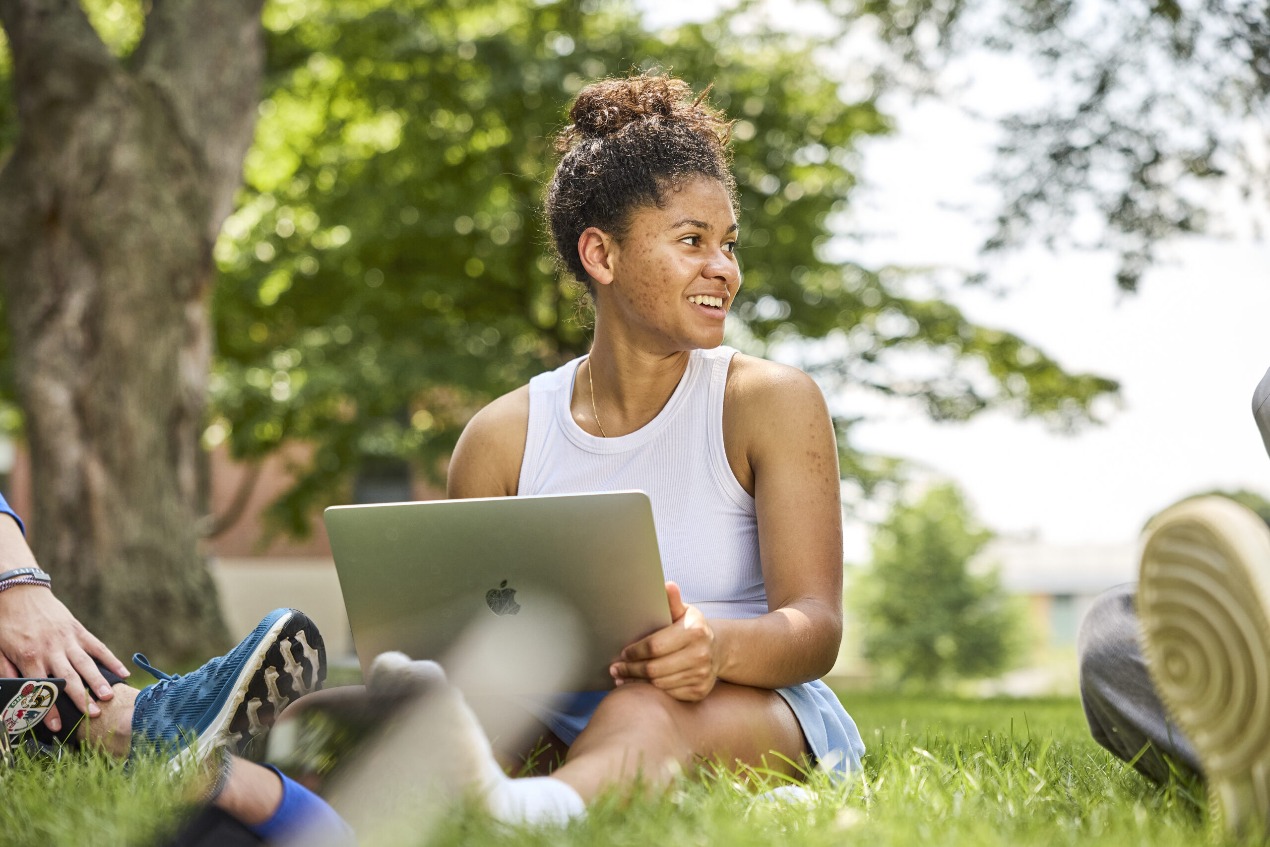 Student using laptop sitting in the grass at Merrimack