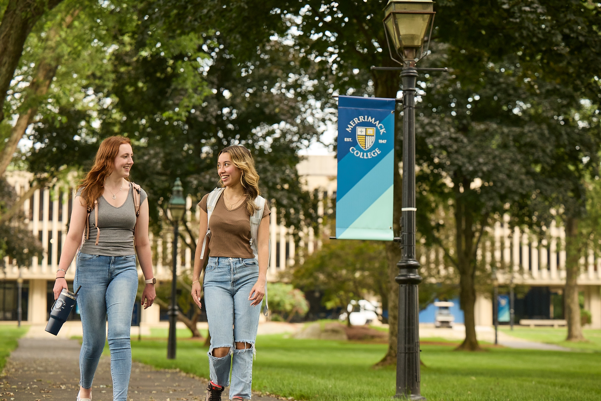 Students walking together across a green Merrimack College campus