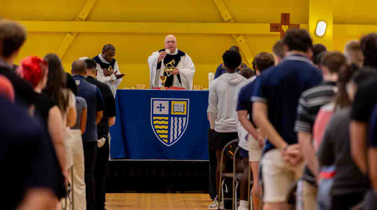 Picture of Fr. Raymond Dlugos, O.S.A., delivering Mass of the Holy Spirit in front of a crowd of Merrimack students.