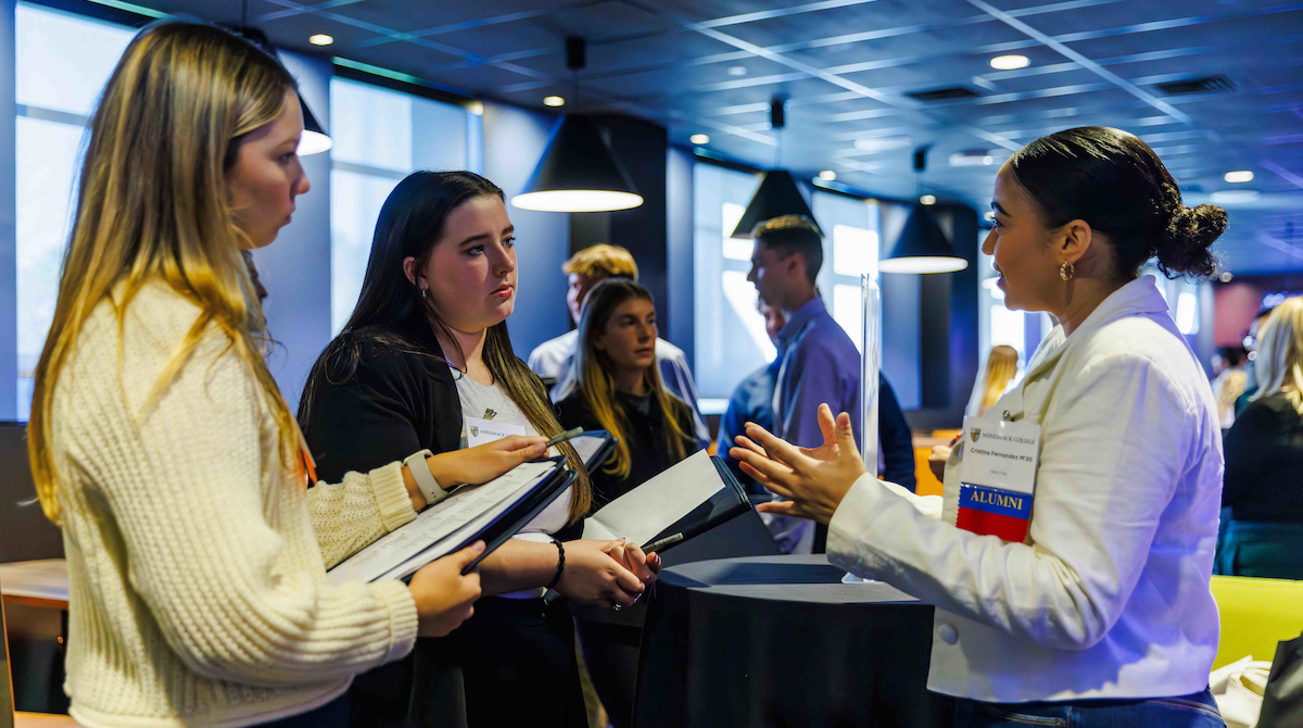 Two Merrimack students speak with a business professional during the college's Professional Development Retreat (PDR) skills fair.