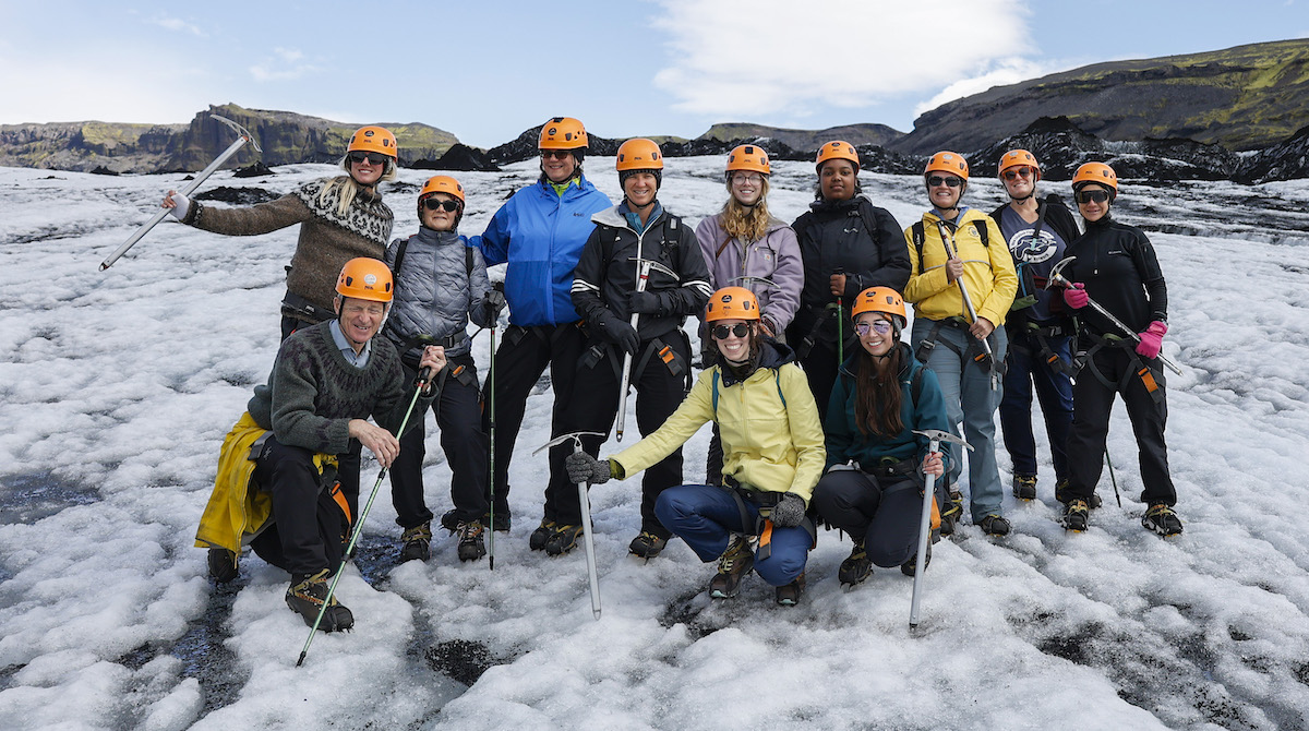 Photo of a group of Merrimack community members posing in hiking gear on top of the Sólheimajökull glacier in Iceland.