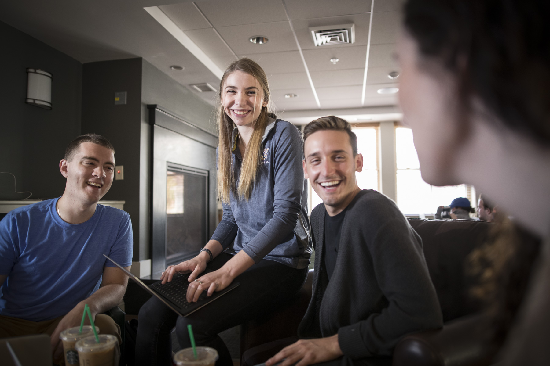 four students sitting in a cafe around a laptop