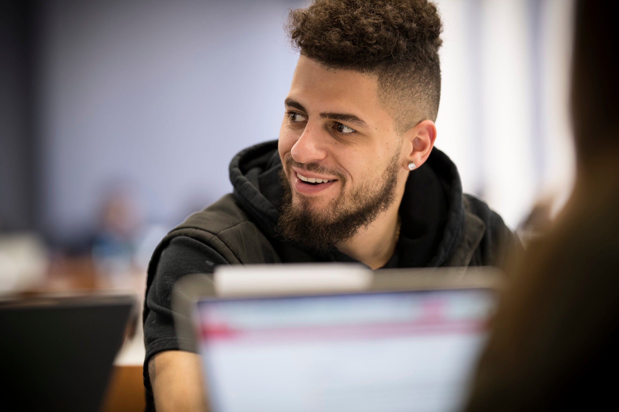 student looking to the left and smiling, with computer in the foreground
