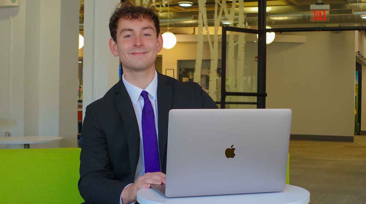 Picture of Alexander Elguezabal ’25 posing behind an Apple laptop.