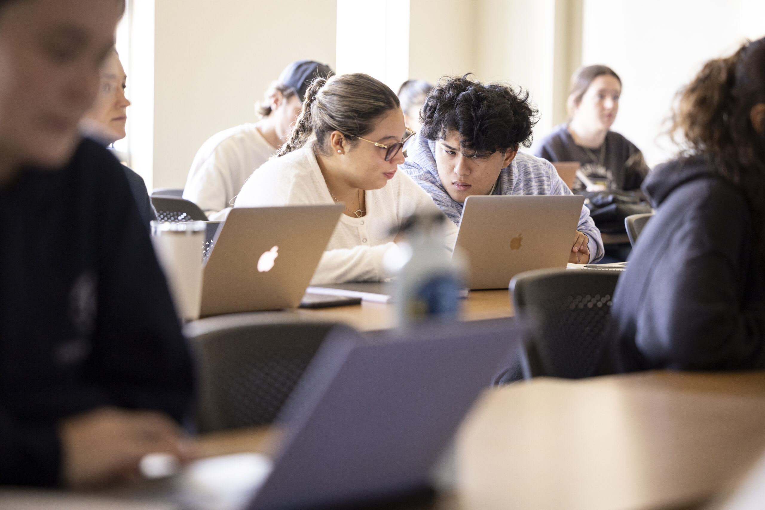 Students sitting together in class using a laptop