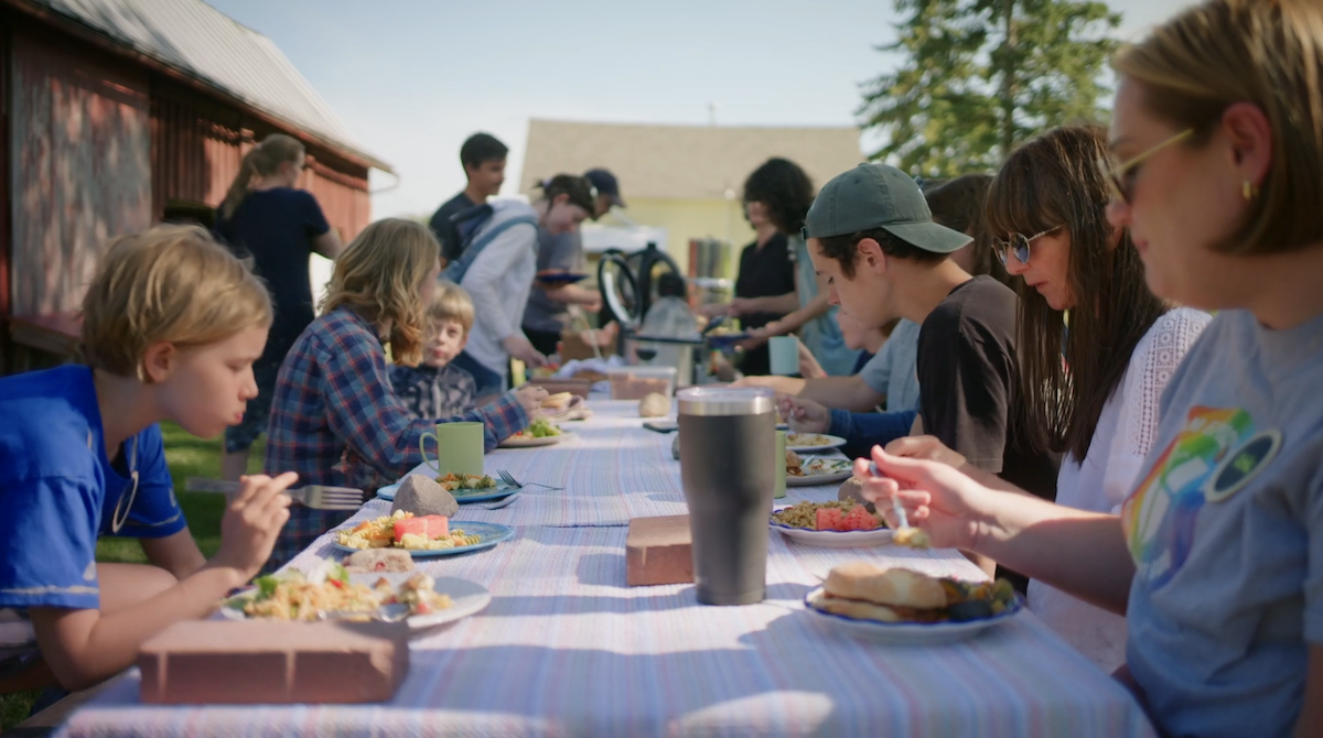 A group of children and adults eating at a picnic table.