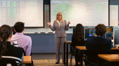 Photo of a Merrimack College professor teaching students in front of charts and graphs.